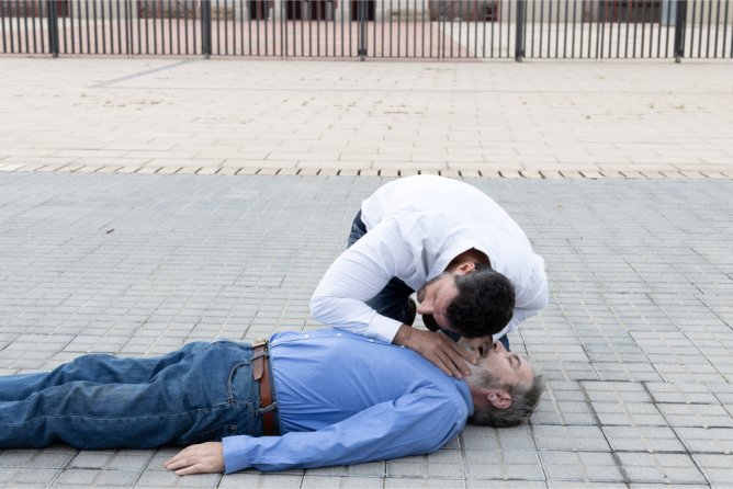 person in a white shirt performing CPR